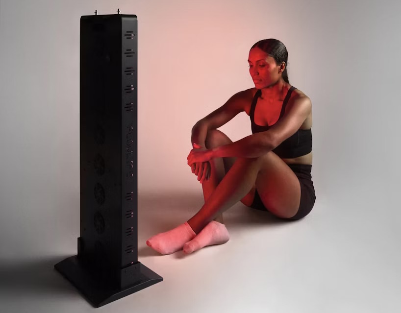 Rödljusterapi för att bekämpa vinterdepression. Kvinna som sitter framför Flowlight Panel Seven Waves