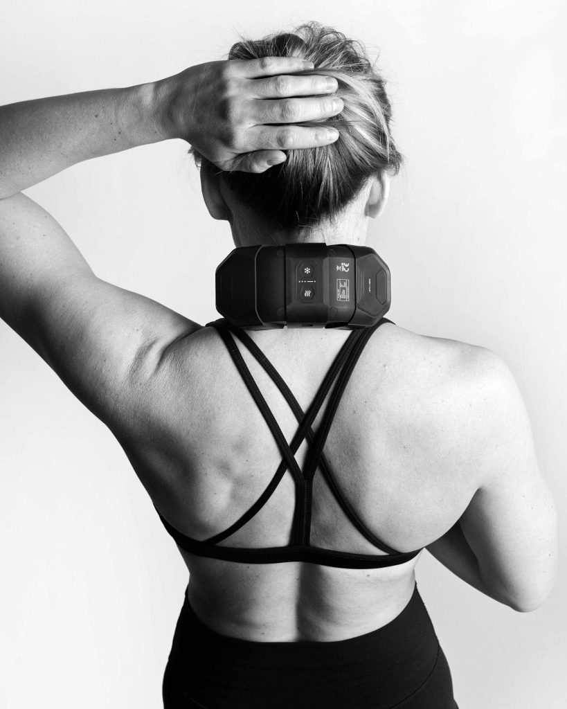 Kvinna använder Flowcontrast Spot Go på sin nacke. Bild bakifrån av henne när hon lyfter vänstra armen.