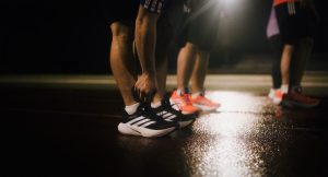 löpare med adidas Supernova Rise 3 Adaptive skor på våt bana i kvällsljus under träning