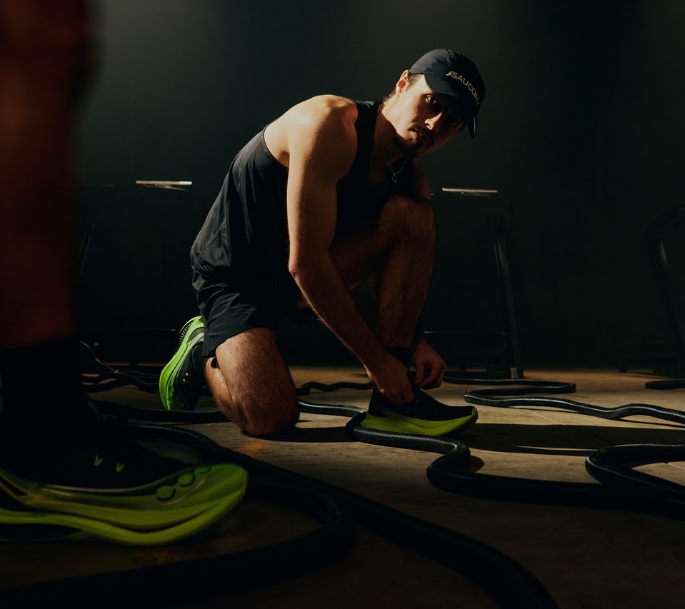 löpare som knyter Saucony Endorphin Pro 5 i mörk träningsmiljö med fokus på prestanda och racingdesign